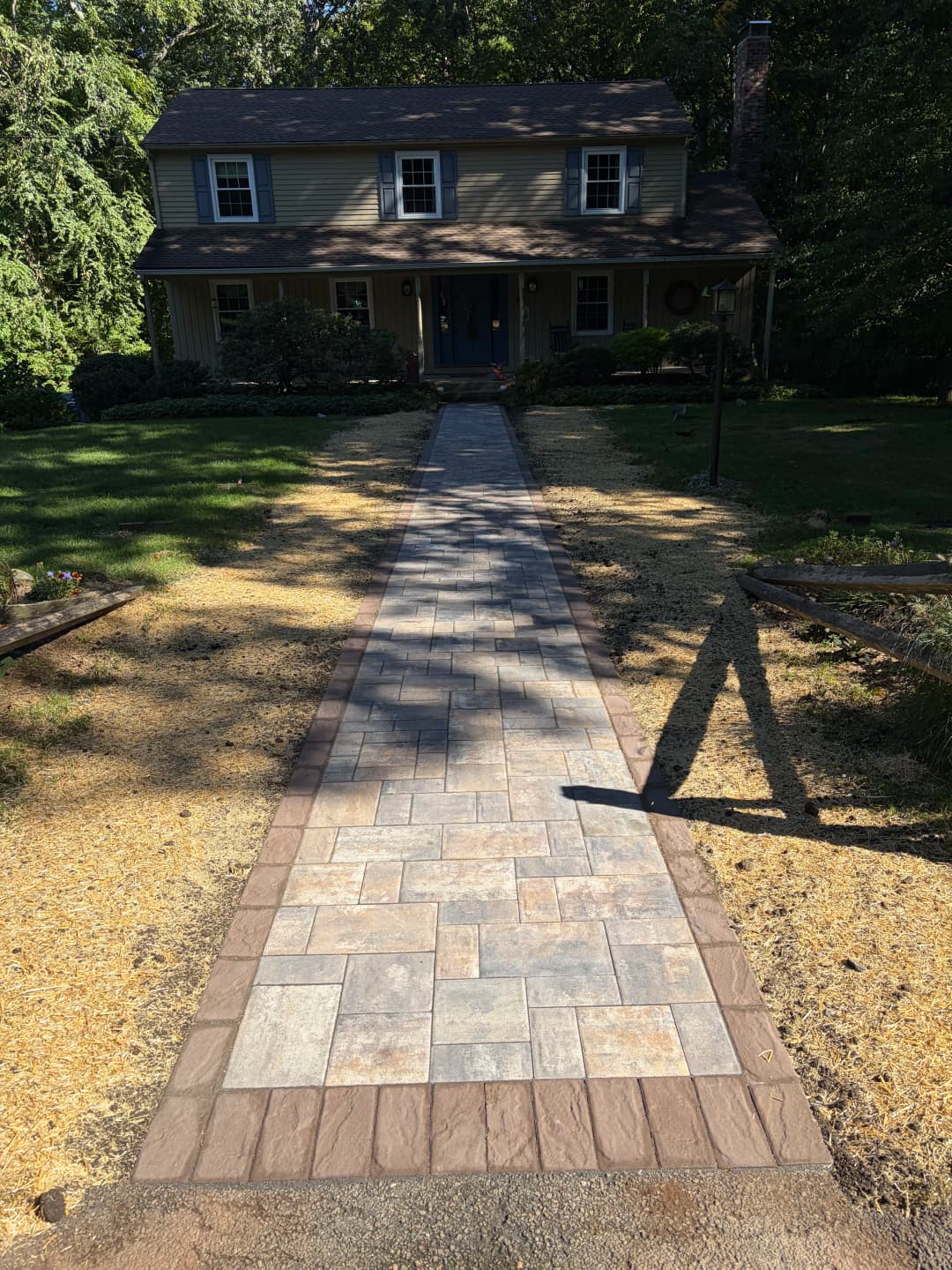 Walkway leading to a house, featuring stone pavers and a landscaped yard.